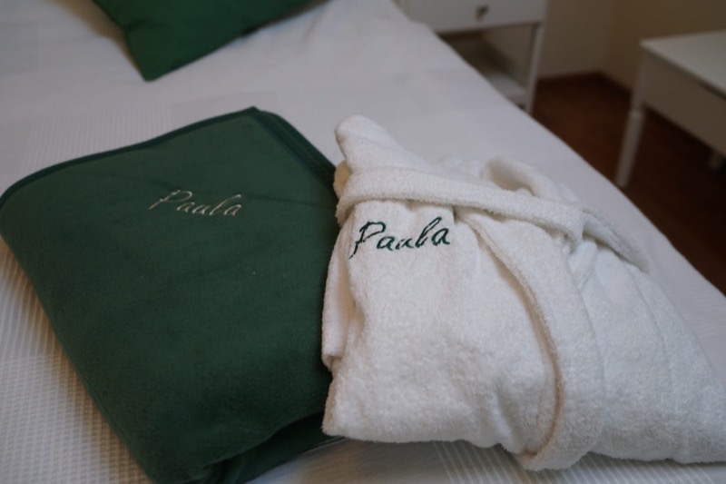 Grüne Decke und weißer Bademantel mit Paula-Stickerei