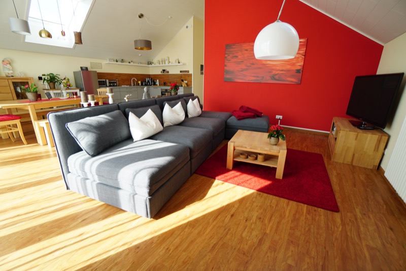 Wohnbereich mit roter Wand und großer Couch